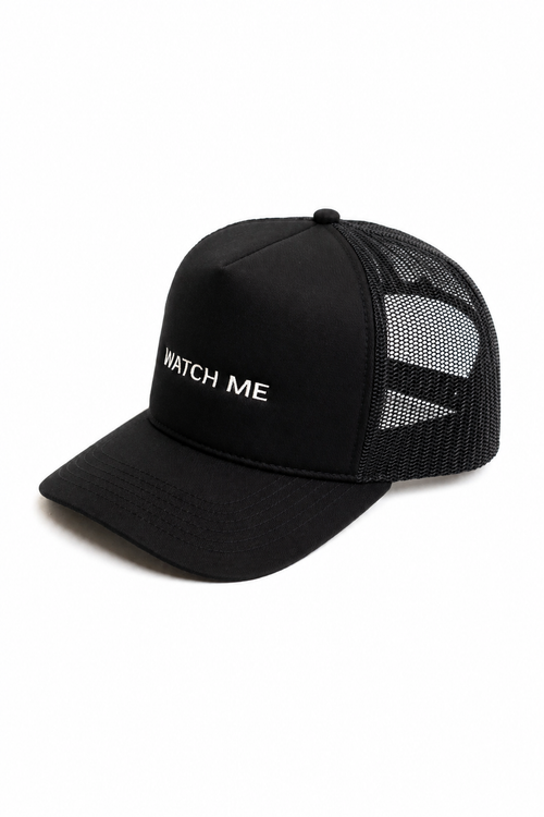 Angled front view of black trucker hat with white embroidered slogan reading "WATCH ME"